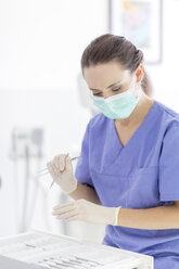 Female dentist holding dental instruments in surgery - MMAF00210