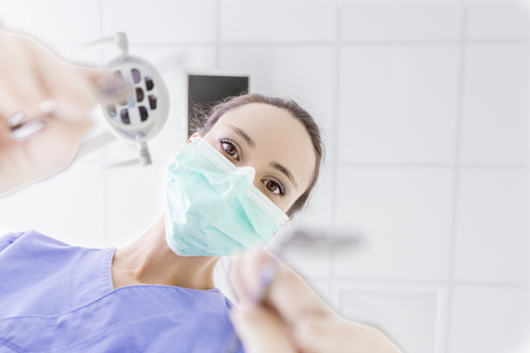 Persönliche Perspektive einer Zahnärztin mit Maske bei der Arbeit, lizenzfreies Stockfoto
