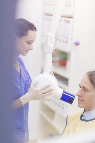 Zahnärztin bei der Röntgenaufnahme eines Patienten, lizenzfreies Stockfoto