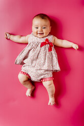 Porträt des glücklichen Baby-Mädchens auf rosa Hintergrund liegend - JRFF01487