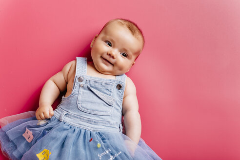 Porträt von lächelnden Baby Mädchen auf rosa Hintergrund liegen - JRFF01488