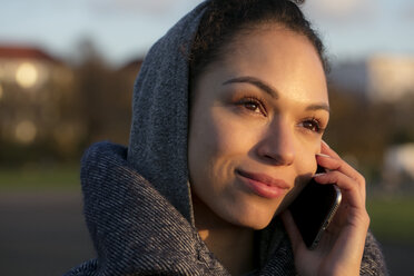 Portrait of smiling young woman on cell phone outdoors - HHLMF00096