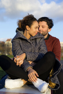 Smiling young couple sitting outdoors - HHLMF00100