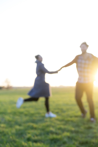 Blurred view of couple on a meadow at sunset stock photo