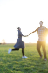 Blurred view of couple on a meadow at sunset - HHLMF00105
