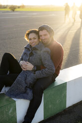 Portrait of smiling young couple sitting outdoors - HHLMF00145