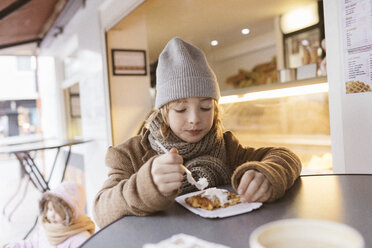 Belgien, Porträt eines Jungen, der im Winter im Freien eine belgische Waffel mit Schlagsahne isst - KMKF00105