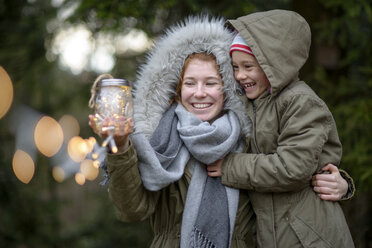 Glückliches Teenager-Mädchen und ihre kleine Schwester mit selbstgebasteltem Geschenk im Freien - LBF01708