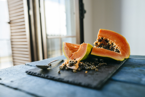 Papaya geschnitten auf Schiefer auf blauem Holz, lizenzfreies Stockfoto