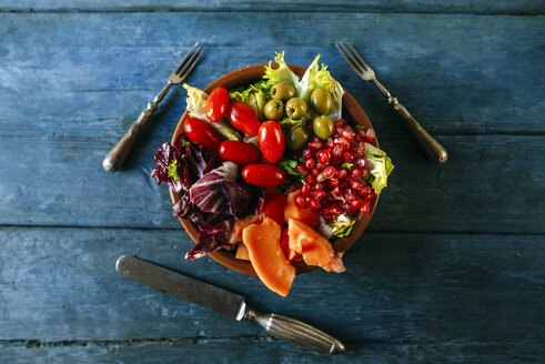 Papayasalat, Granatapfel, Kopfsalat, Tomate, Oliven und Endivie auf blauem Holz - KIJF01819