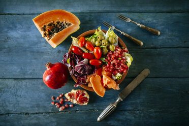 Papaya salad, pomegranate, lettuce, tomato, olives and endive on blue wood - KIJF01820