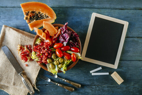 Papayasalat, Granatapfel, Kopfsalat, Tomate, Oliven und Endivie mit Schiefer, auf blauem Holz - KIJF01822