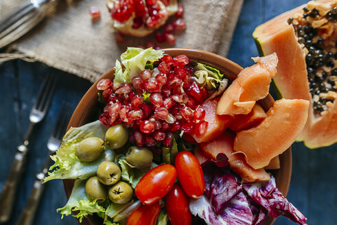 Nahaufnahme von Papayasalat, Granatapfel, Kopfsalat, Tomaten, Oliven und Endivien in einer Schüssel - KIJF01823