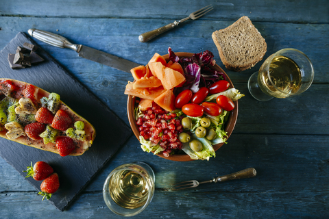 Salat mit Tomate, Granatapfel, Papaya und Oliven, mit Papaya und einem Glas Wein, lizenzfreies Stockfoto