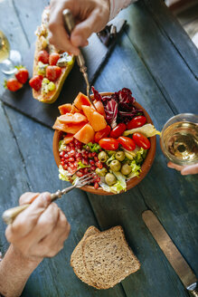 Nahaufnahme von Frauenhänden, die einen Salat aus Tomaten, Granatäpfeln, Papaya und Oliven essen - KIJF01835