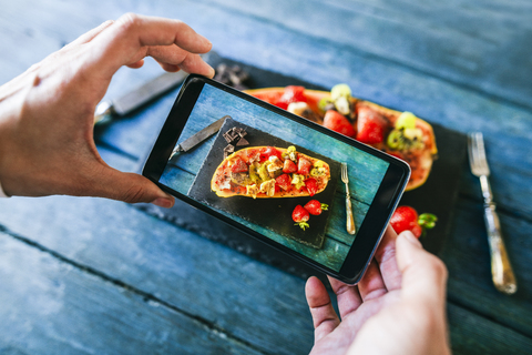 Nahaufnahme von Frauenhänden, die ein Foto mit einer Vielzahl von Früchten machen, die in einer Papaya serviert werden, lizenzfreies Stockfoto