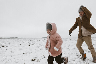 Bruder und kleine Schwester spielen zusammen auf einer schneebedeckten Wiese - KMKF00113