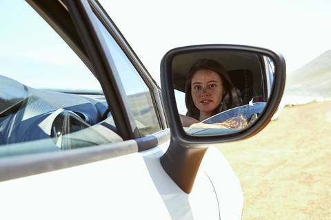 Reflection of young woman in wing mirror of a car stock photo