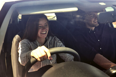 Glückliche junge Frau mit Freund beim Autofahren - SRYF00700