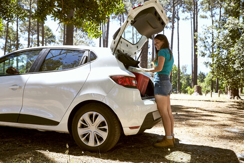 Smiling young woman loading a car - SRYF00702