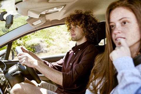 Junger Mann mit Freundin beim Autofahren, lizenzfreies Stockfoto