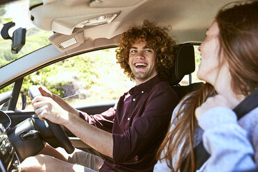 Laughing young man driving car looking at his girlfriend - SRYF00705