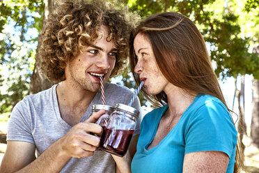 Lächelndes junges Paar bei einem Drink im Wald - SRYF00712