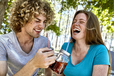 Laughing young couple having a drink in forest - SRYF00713