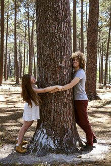 Happy young couple hugging a tree in forest - SRYF00722