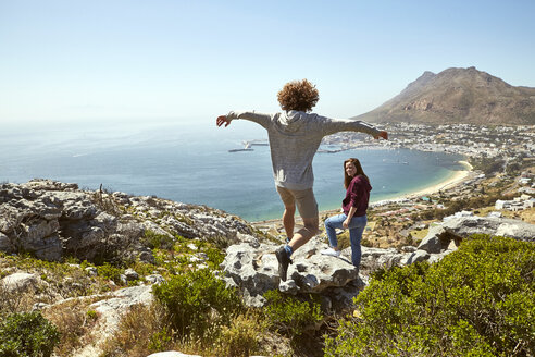 South Africa, Cape Town, young couple on a trip at the coast with man jumping - SRYF00727