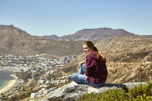 South Africa, Cape Town, young woman sitting at the coast looking at view - SRYF00730