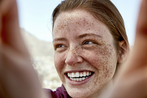 Porträt einer lachenden jungen Frau mit Sommersprossen im Freien, lizenzfreies Stockfoto