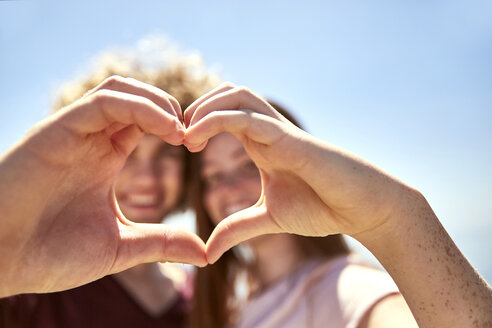 Happy young couple shaping a heart with their hands - SRYF00749