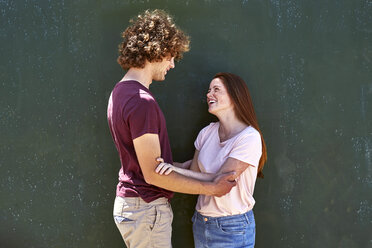 Smiling young couple in front of a green wall - SRYF00760