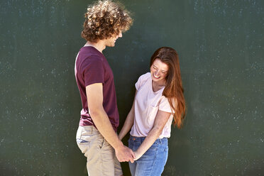 Happy young couple in front of a green wall - SRYF00761