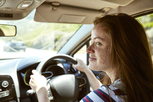 Lächelnde junge Frau mit Sommersprossen fährt Auto und schaut zur Seite - SRYF00767