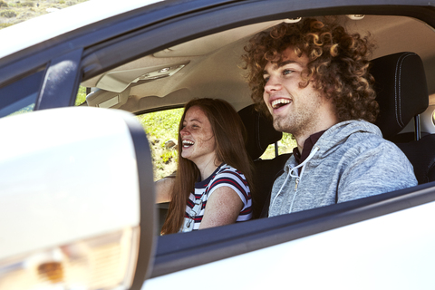 Laughing young woman with boyfriend driving car stock photo