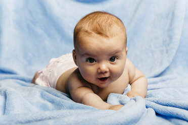 Portrait of smiling baby girl lying on light blue blanket - JRFF01491