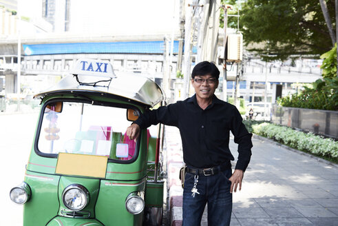 Thailand, Bangkok, Tuk-Tuk-Fahrer steht neben seinem Fahrzeug auf der Straße - IGGF00341