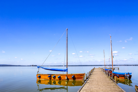 Deutschland, Niedersachsen, Steinhuder Meer mit leerem Steg und vertäuten Segelbooten, lizenzfreies Stockfoto