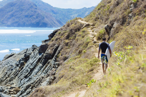 Indonesien, Lombok, Surfer, der an der Meeresküste spazieren geht - KNTF00943