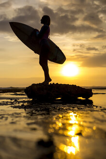 Indonesien, Bali, Silhouette einer jungen Frau mit Surfbrett in der Abendsonne - KNTF00950