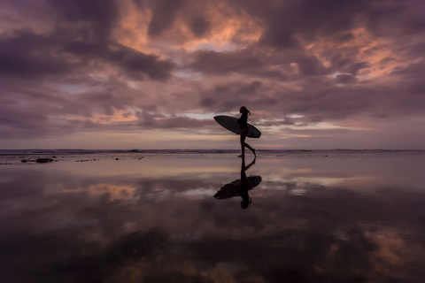 Indonesien, Bali, junge Frau mit Surfbrett am Abend, lizenzfreies Stockfoto