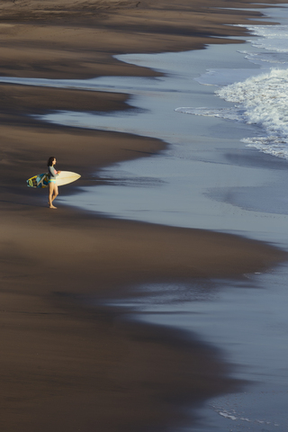 Indonesien, Bali, junge Frau mit Surfbrett, lizenzfreies Stockfoto