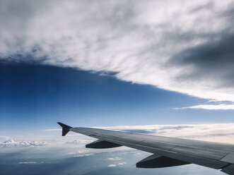 Blick auf die Tragfläche eines Flugzeugs, das in grauen Wolken am Himmel fliegt. - BZF00378