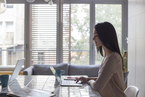 Frau mit Laptop bei der Arbeit zu Hause, lizenzfreies Stockfoto