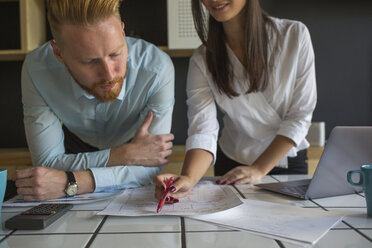 Man and woman with laptop studying plans on table at home - MOMF00372