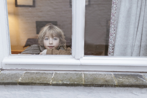 Portrait of pensive boy looking out of window stock photo