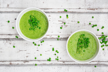 Two bowls of pea soup and peas on wood - LVF06585