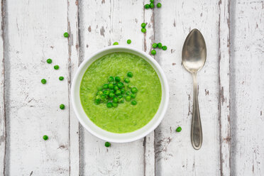 Bowl of pea soup, spoon and peas on wood - LVF06586